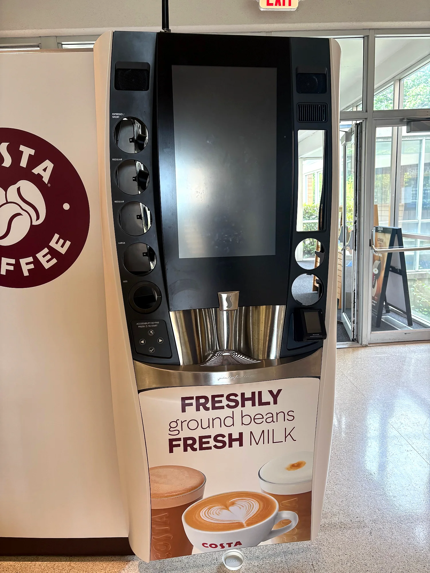 Cream-and-burgundy Costa Coffee self-serve machine with the beans logo and Freshly Ground Beans Fresh Milk panel