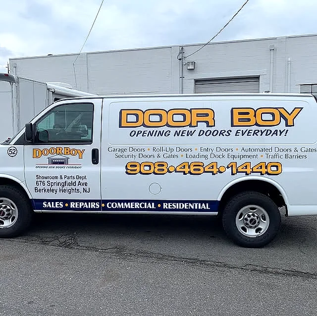 White Door Boy cargo van with blue and orange lettering listing garage-door services and a large phone number