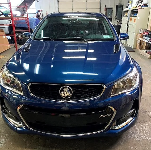 Metallic blue performance sedan with a fresh color-change wrap inside the Applied Graphics shop
