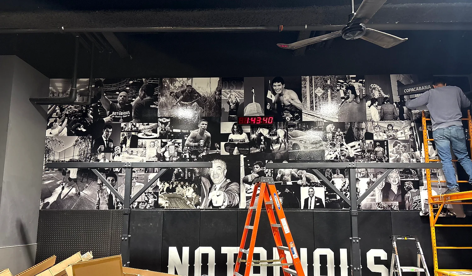Large black-and-white photo-collage wall mural with NOTORIOUS lettering inside a boxing gym
