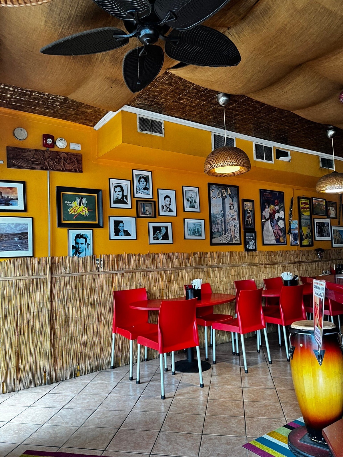 Inside Cha Cha Cha — warm yellow walls, red chairs, framed photos of Cuban icons